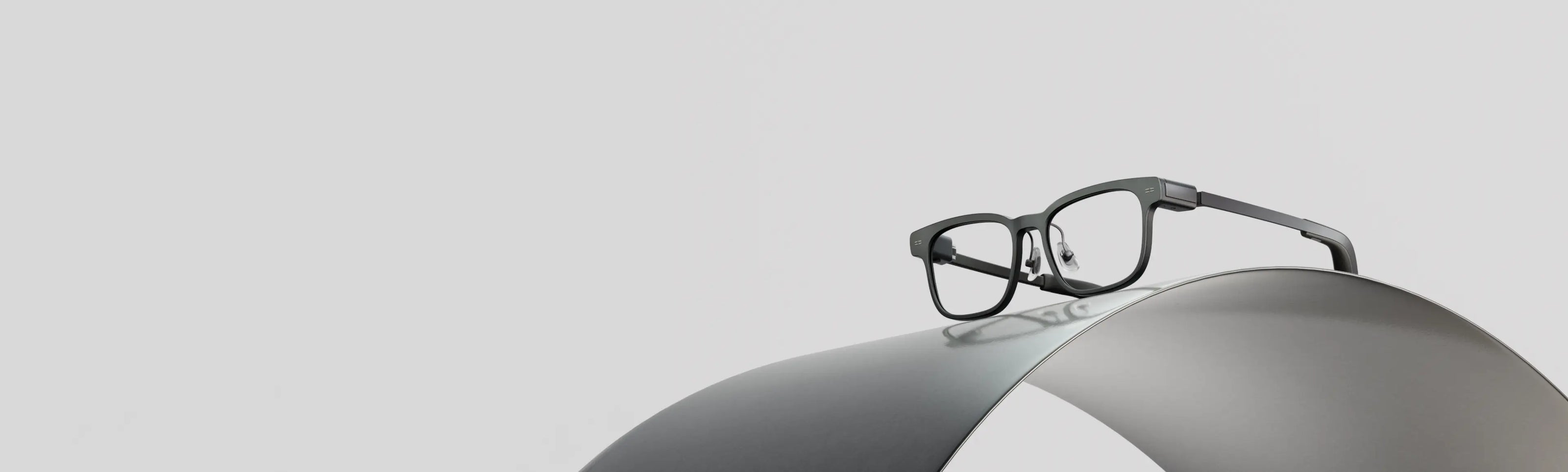 MemoMind smart eyeglasses on a metallic surface with a light gray background